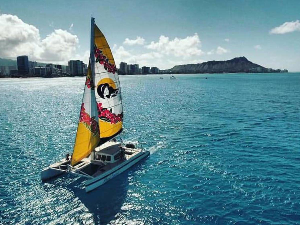 A catamaran sailing off Waikīkī with Diamond Head behind
